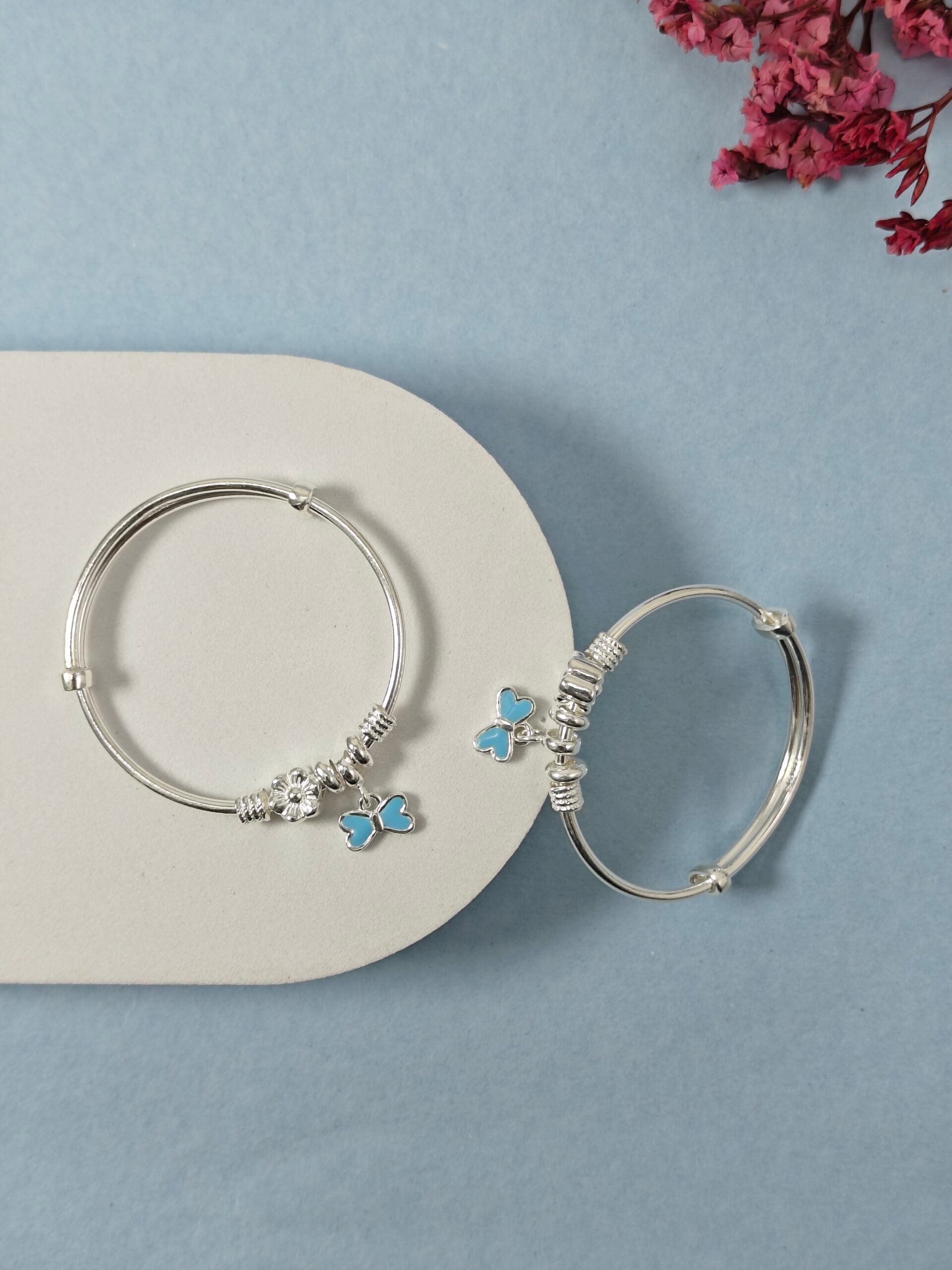 Silver hoop earrings with butterfly charms on a light blue background